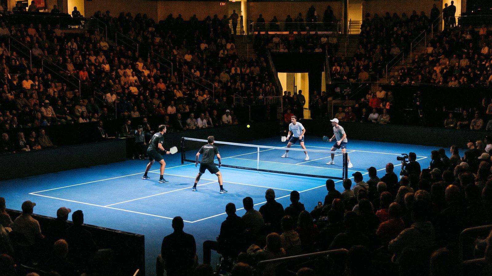 Packed arena crowd watching a floodlit pickleball doubles final